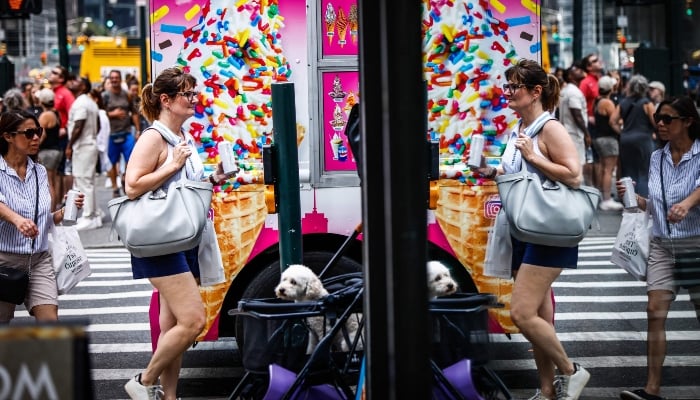 People walk past an ice cream truck in New York on June 22, 2025 as a heatwave affects the area. — AFP