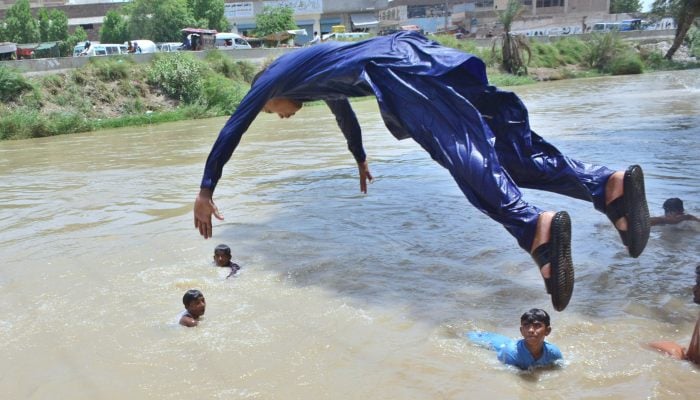 Youngsters dive and swimming in a water canal to beat the scorching heat in Hyderabad, June 17, 2025. — APP