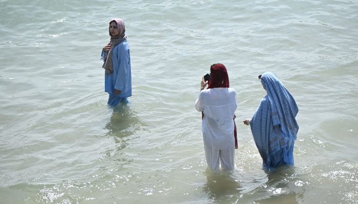 A paddler has a photo taken as the temperature rises in Bournemouth on the south coast of England on June 29, 2025. — AFP