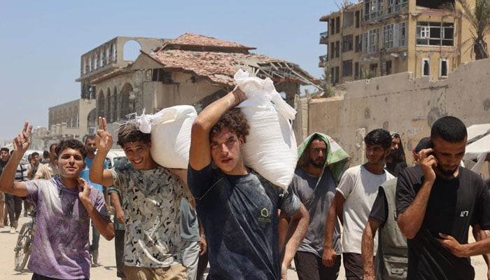 People make their way along al-Rashid street in western Jabalia after receiving humanitarian aid from an aid distribution point in the northern Gaza Strip in this image released on July 23, 2025. — AFP