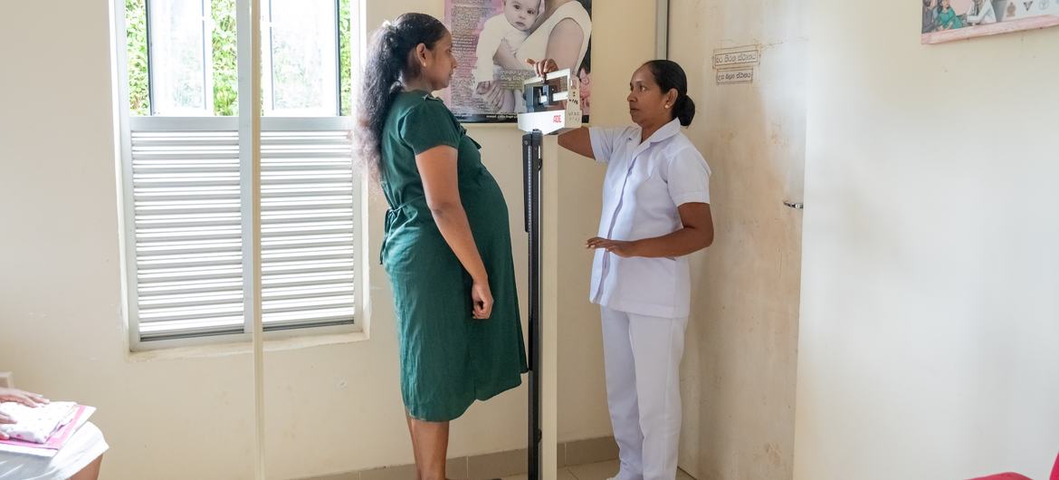 A nurse checks a pregnant woman's weight and vital signs at a clinic in Galigamuwa, Sri Lanka.