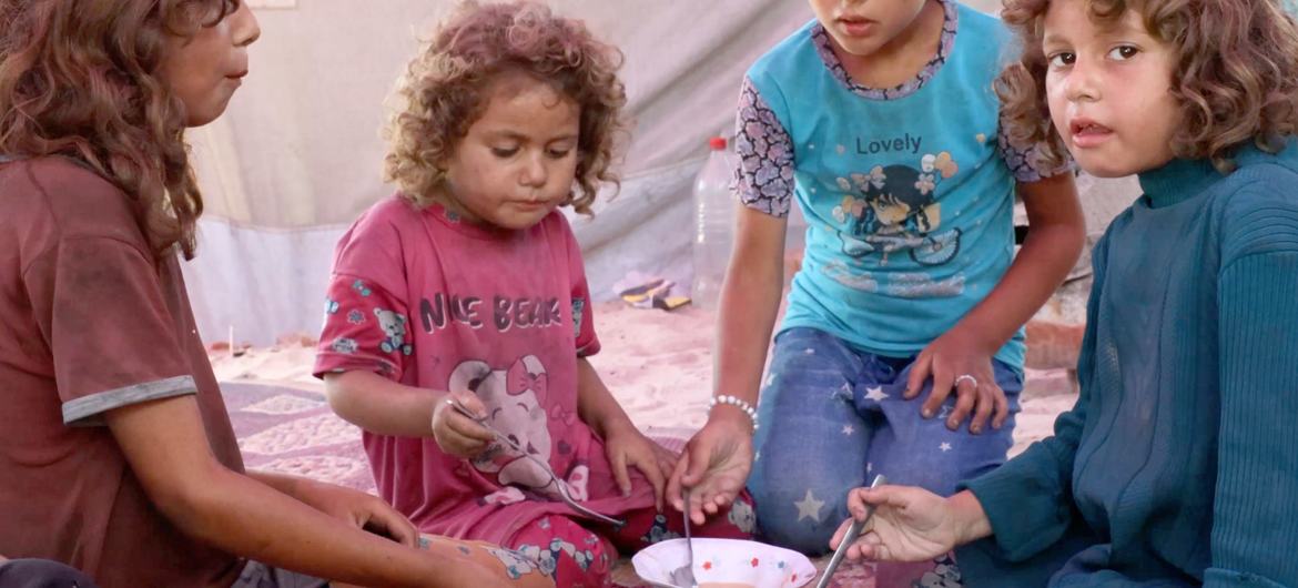 Hiyam's daughters eating a lunch of lentil soup, without bread, where they live, inside a destroyed building.