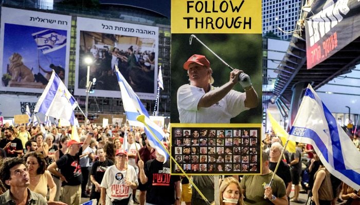 A demonstrator poses with a zipper covering her mouth while holding a golf club in one hand and a sign urging an intervention from US President Donald Trump, during an anti-government protest, outside the Israeli Defence Ministry headquarters in Tel Aviv on August 2, 2025. — AFP
