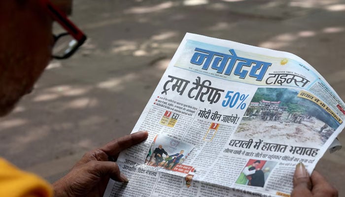 A man reads a newspaper with reports on tariff after US President Donald Trump announced an additional 25% tariff on Indian goods, alongside a market in New Delhi, India, August 7, 2025. — Reuters