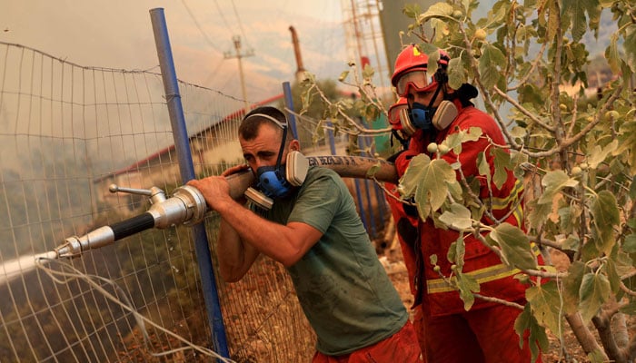 Firefighters spray water on a wildfire near the town of Delvine, south-east Albania, on August 13, 2025. — AFP