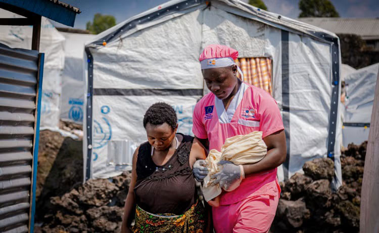 Midwife Loti Kubuya Mielor assists a newly arrived displaced woman who gave birth in a shelter in Goma, DR Congo.