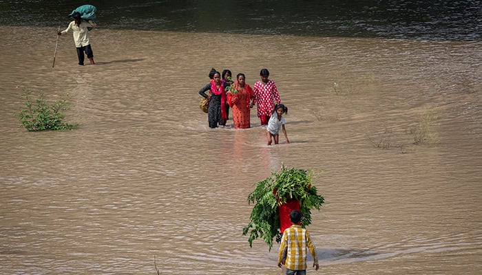 People wade through a flooded road with their belongings after a rise in the water level of river Yamuna due to heavy monsoon rains, in New Delhi, India, September 3, 2025. — Reuters