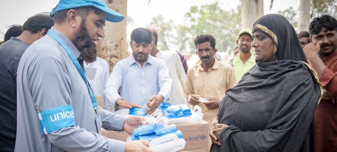 A UNICEF staff member distributes hygiene kits and water purification tablets to flood affected families in Jhang district, Punjab.