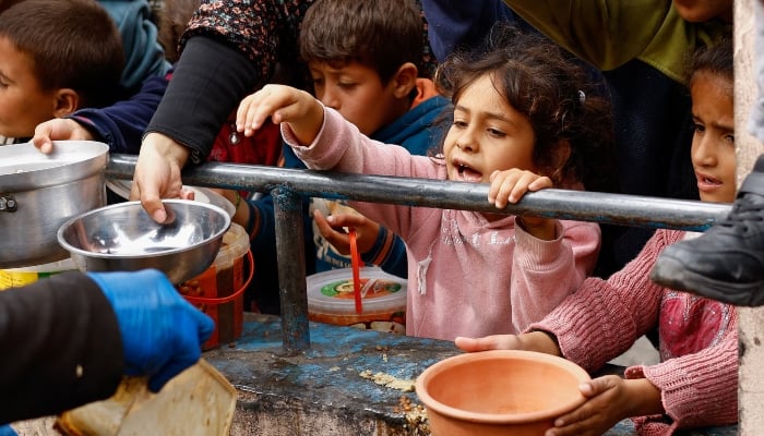 Palestinian children wait to receive food cooked by a charity kitchen amid shortages of food supplies in Rafah, in the southern Gaza Strip, February 13. — Reuters