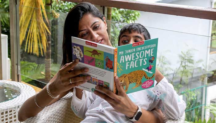 Vidushi Malhotra, a pollution refugee and founder of an education advisory organisation, reading a children´s book to her son at their residence in Goa on September 27, 2025. — AFP