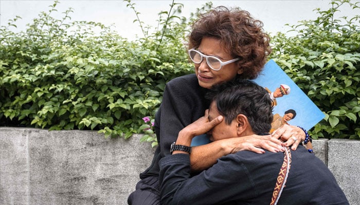 People react as they hold portraits of Thailand´s former queen Sirikit in front of Chulalongkorn Hospital in Bangkok on October 25, 2025. — AFP