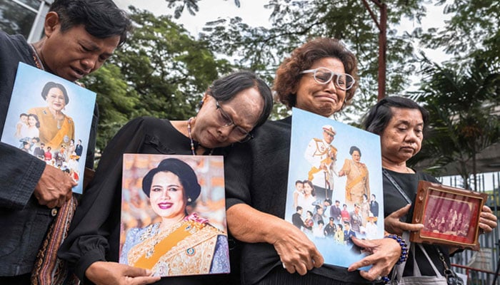 People hold portraits of Thailand´s former Queen Sirikit as they gather in front of Chulalongkorn Hospital, where she passed away, in Bangkok on October 25, 2025. — AFP
