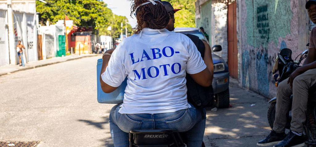 A 'labo moto' health worker travels by motorbike to visit a patient.