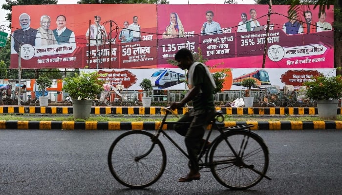 In this photograph taken on November 1, 2025, a cyclist rides past a banner featuring Narendra Modi (L), Indias Prime Minister and leader of the Bharatiya Janata Party (BJP) and Nitish Kumar (2L), Chief Minister of Bihar state and leader and election candidate of the Janata Dal United (JDU) party, displayed along a street in Patna, ahead of the state assembly elections. — AFP