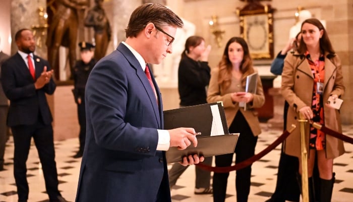 US Speaker of the House Mike Johnson, Republican of Louisiana, reviews his papers while on his way to talk with reporters after the vote to re-open the government at the US Capitol in Washington, DC, November 12, 2025. â AFP