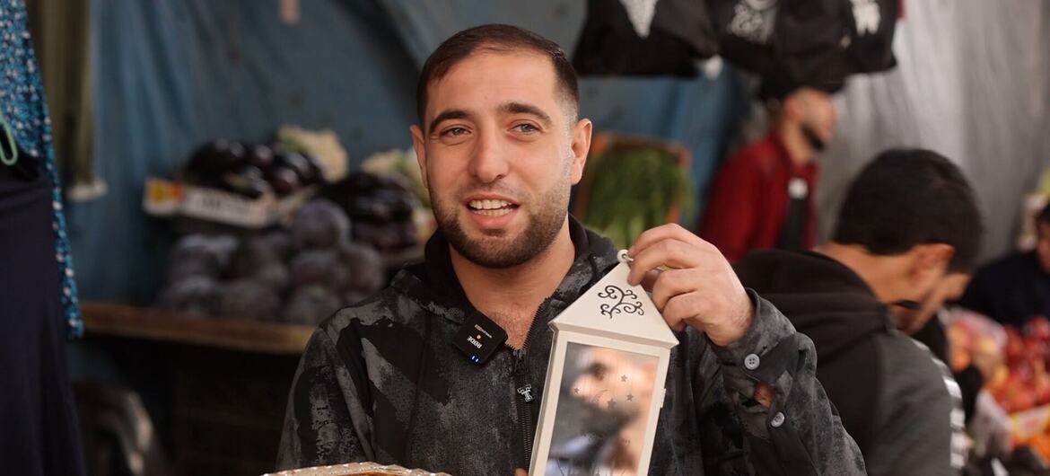 A man in Gaza holds a decorative lantern and a golden box during Ramadan festivities at a market.