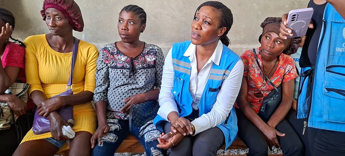 Director of OCHA Crisis Response Division Edem Wosornu sits on a bench with displaced women in Delmas, Haiti, during a visit to a Community Resource Centre in March 2026.